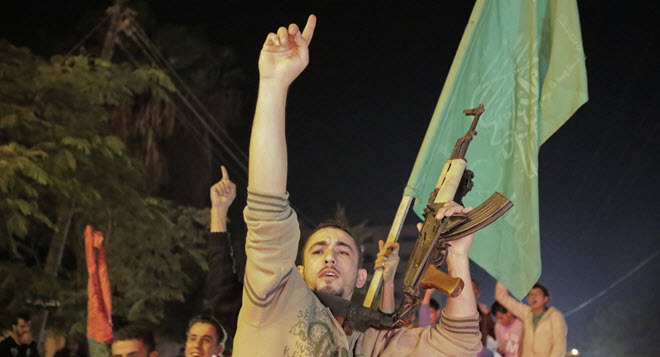 فلسطيني يحمل بندقيته في الهواء بينما كان يحتفل بعيد وقف إطلاق النار في غزة